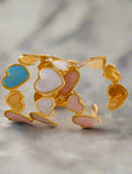 Gold bracelet with heart-shaped charms on a light background